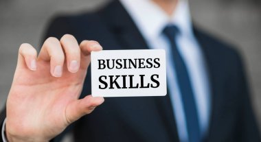 İş adamı beyaz kart üzerinde 'iş becerileri' sözcüğünü sunar