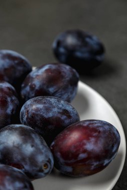 Koyu arkaplanda bir tabakta mavi erik. Mesaj için yer. Fotokopi alanı olan meyve arkaplanı. Durgun yaşam yemeği.