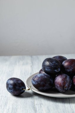 Ahşap bir masada tabakta mavi erik. Mesaj için yer. Fotokopi alanı olan meyve arkaplanı. Durgun yaşam yemeği.