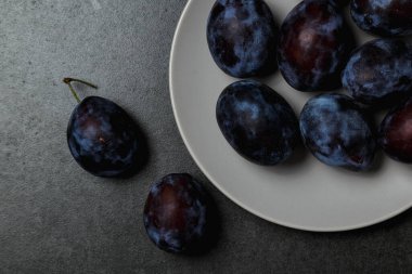 Koyu arkaplanda bir tabakta mavi erik. Üst görünüm, metin için yer. Fotokopi alanı olan meyve arkaplanı. Durgun yaşam yemeği.