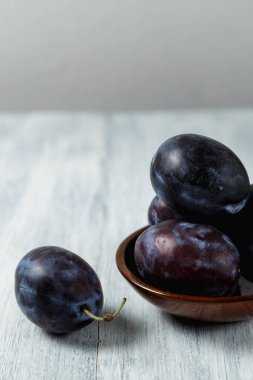 Ahşap bir masada tabakta mavi erik. Mesaj için yer. Fotokopi alanı olan meyve arkaplanı. Durgun yaşam yemeği.