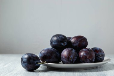 Ahşap bir masada tabakta mavi erik. Mesaj için yer. Fotokopi alanı olan meyve arkaplanı. Durgun yaşam yemeği.