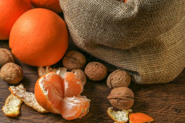 Olgun, lezzetli ve sulu portakallar, mandalinalar ve masada cevizler..