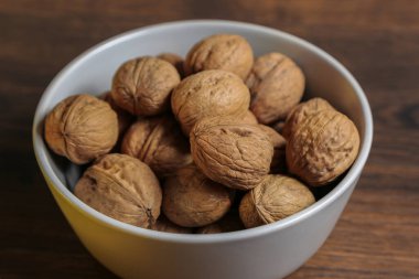 Limonlar, portakallar ve cevizler ahşap bir masada gri bir kasede