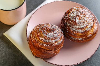 Tarçın ve hindistan cevizli limonlu çörekler gri bir masada pembe bir tabakta