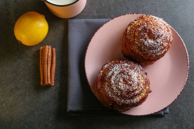 Tarçın ve hindistan cevizli limonlu çörekler gri bir masada pembe bir tabakta