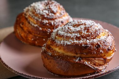 Tarçın ve hindistan cevizli limonlu çörekler gri bir masada pembe bir tabakta