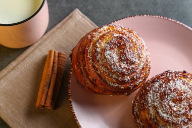 Tarçın ve hindistan cevizli limonlu çörekler gri bir masada pembe bir tabakta
