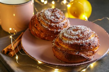 Tarçın ve hindistan cevizli limonlu çörekler gri bir masada pembe bir tabakta