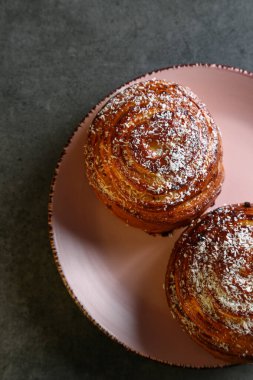 Tarçın ve hindistan cevizli limonlu çörekler gri bir masada pembe bir tabakta
