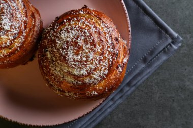 Tarçın ve hindistan cevizli limonlu çörekler gri bir masada pembe bir tabakta