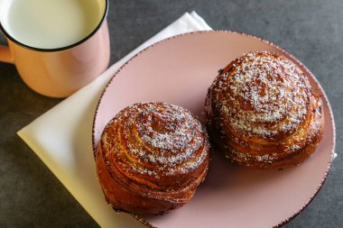 Tarçın ve hindistan cevizli limonlu çörekler gri bir masada pembe bir tabakta