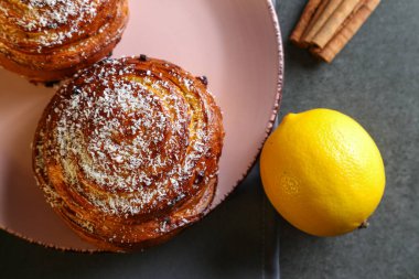 Tarçın ve hindistan cevizli limonlu çörekler gri bir masada pembe bir tabakta