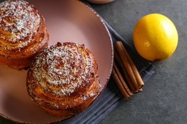Tarçın ve hindistan cevizli limonlu çörekler gri bir masada pembe bir tabakta