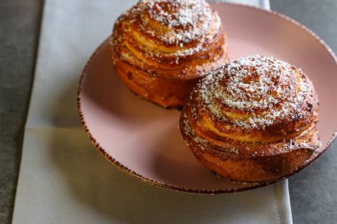 Tarçın ve hindistan cevizli limonlu çörekler gri bir masada pembe bir tabakta