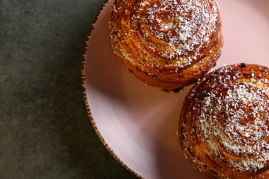 Tarçın ve hindistan cevizli limonlu çörekler gri bir masada pembe bir tabakta