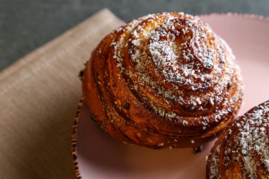 Tarçın ve hindistan cevizli limonlu çörekler gri bir masada pembe bir tabakta