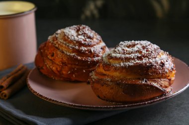 Tarçın ve hindistan cevizli limonlu çörekler gri bir masada pembe bir tabakta