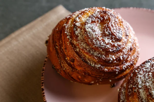 Tarçın ve hindistan cevizli limonlu çörekler gri bir masada pembe bir tabakta