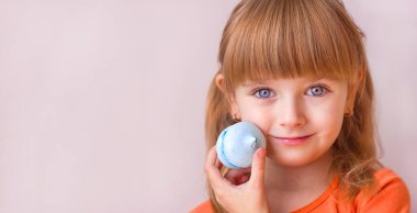 Güzel küçük kız elinde mavi bir tatlı makaronu tutuyor. Yakın plan, tatlı pastalar. Çocukluk duyguları, seçici odaklanma.