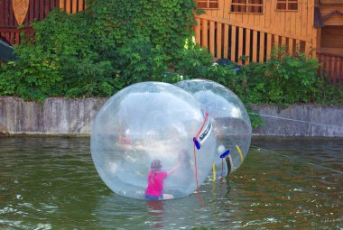 Lviv Ukraine - 06 13 2022: Fun game on the water zorbing, children swim and have fun in a transparent inflated plastic balloon, active pastime on vacation