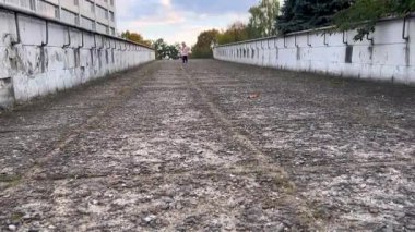 Şık giyinmiş şirin bir kız dağdan koşarak şehir evlerinin ve ağaçların arkasına doğru koşar. Çocuklarla aktif yürüyüşler, mutlu çocukluk, seçici odaklanma.