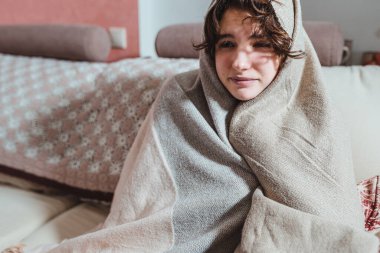 Genç kadın başıyla sıcak bir battaniyeye sarılmış. Genç kız başını yün bir ekose kumaşa sarmış, neşeli bir ruh hali içinde, soğuk bir odada, sıcak bir atkıyla.