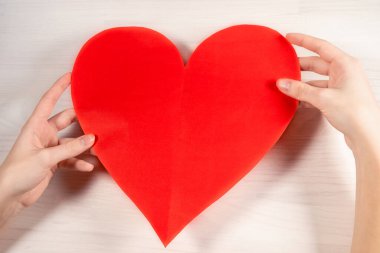 Kağıt kırmızı kalp ellerinde. Kırmızı kağıt kalp şeklinde beyaz bir bayanın güzel elleri. Yukarıdan bak. Aşk konsepti, sevgililer günü, büyük aşk hissi.