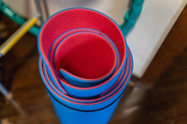 Kırmızı ve maviyle kaplanmış fitness paspası, duvar çubuğu ve hulahop 'un yanında. Yukarıdan bak. Ev hayatı için spor ekipmanları