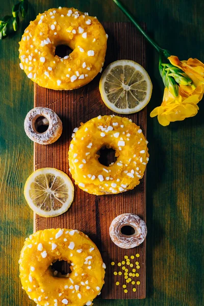 Şeker rengi limon jöleli çörekler, bayram süsleriyle, limon dilimleri, frezya çiçekleri, karatahta desenli. Limonlu şekerli donutlar. Yukarıdan bak. Düz yatıyordu