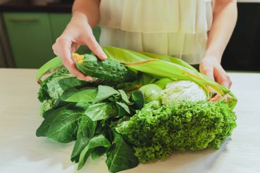 Mutfak masasındaki alışveriş poşetinde taze sebze ve salata. Tanımlanamayan bir kadının elleri ev mutfağında alışveriş torbasını düzenliyor. Diyet gıda konsepti, sebze diyeti