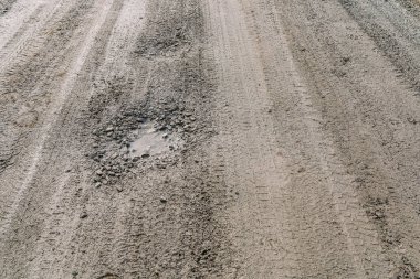 Asfalt kaldırımı olmayan, kil ve molozdan yapılmış toprak yol, çukurlar ve çukurlarla dolu su birikintileri, yağmurdan sonra ıslak su birikintileri. Yıkım konsepti, off-road, geçilemez yollar