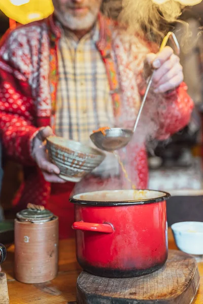 波兰人在家里烹调的食物 穿着休闲装的男人把大锅里的汤倒进瓷盘里 装上勺子 — 图库照片