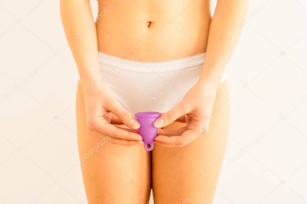 woman holding menstrual cup on front of her private parts. Feminine hygiene alternative product instead of tampon during period. Menstruation, critical days, women periods. Zero waste, eco, ecology.