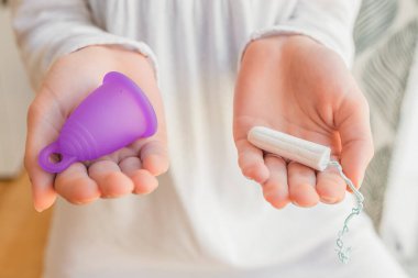 hands of young girl with tampon and menstrual cup, using cup during period. Eco, zero waste
