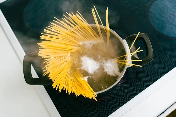El, spagettiyi kaynar suyun içine koyar. Makarna, bolonez tarifi için malzeme. Glütensiz makarna, sağlıklı yemek.,
