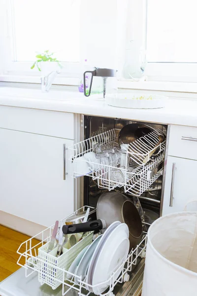 Dishwasher filled with dirty dishes with open door in home kitchen. fragment of kitchen with white facades, with kitchen sink, dishwasher, concept of repairing household appliances, home real interior, home routine