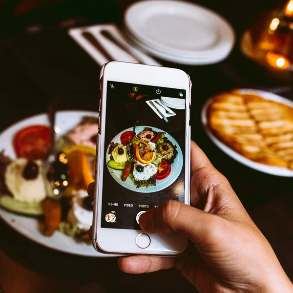 Selfie food on a smartphone. Greek varied appetizing cuisine, cold appetizers, spreads and sauces. Take picture of food in restaurant on smartphone, amateur photography