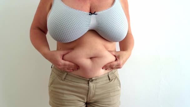 クローズアップ太りすぎの中年40代の脂肪の女性は 余分な脂肪 ショートパンツやブラジャーを身に着けていると弱々しい腹の皮膚を示しています 腹をぶら下げて 結果不健康な食事 不活性 筋肉のポンプ不足 — ストック動画