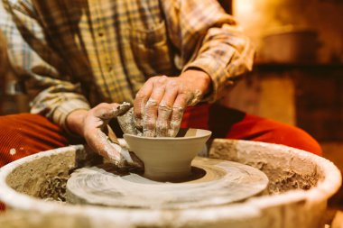 pottery in workshop of ceramist. potter's hands working with clay on potter's wheel, forming bowl. Traditional pottery, craft handicrafts, authentic atmosphere