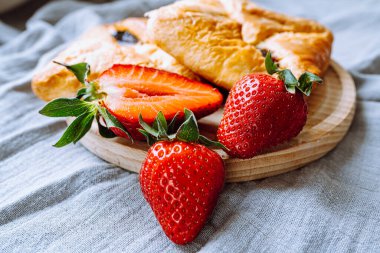 Sweet puff pastry with strawberry jam. Close-up summer dessert sweet envelopes with jam from fresh strawberries on round wooden board. soft focus