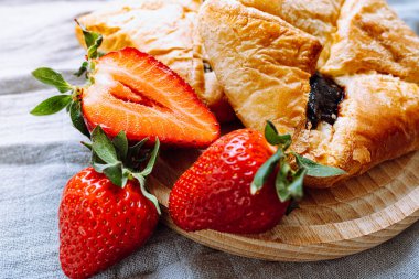 Sweet puff pastry with strawberry jam. Close-up summer dessert sweet envelopes with jam from fresh strawberries on round wooden board. soft focus