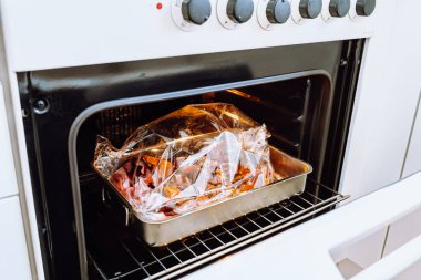 Cooking meat in plastic bag for baking. no plastic concept. Fresh mutton or beef meat packed in spice sleeve ready to bake, seen through open oven door. Festive dinner, healthy food without vegetable fat and frying clipart
