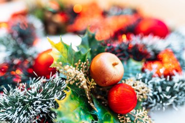 - Noel çelengi. Kırmızı toplarla süslenmiş Noel süslemeleri ve karla süslenmiş böğürtlenler, yakın plan.