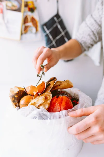 woman puts kitchen waste into compost bin. Compost bin. sustainable lifestyle. Vegetable, fruit peel, cooking waste collected in trash can for recycling