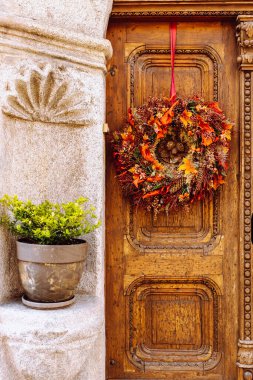 Antika ahşap oyma kapı DIY sonbahar dekoratif çelengi, taş vazad yanında çiçek saksısı