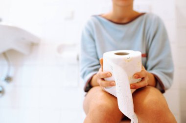 Kadının silueti bulanık arka planda tuvalette oturuyor. Hasta, sağlıksız bir kadın, genç, ishal, kabızlık ve kistik iltihabı var. Adet döneminde karın ağrısı. Sağlık ve acı konsepti