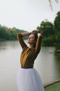 Kharkiv, Ukrayna. 09.19.2021. Şiddetli yağmurda şemsiyeyle nehrin kenarında yürüyen komik bir çiftin aşk hikayesi. Beyaz etekli, sarı kazaklı hoş bir adam ve kadın. Aile tatili ve birliktelik, randevu