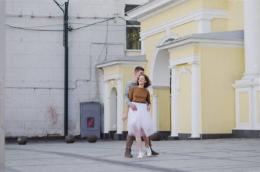 Kharkiv, Ukrayna. 09.19.2021. Tarz sahibi komik bir çiftin aşk hikayesi: tişörtlü genç bir adam. Ve beyaz etekli, sarı kazaklı hoş bir kadın. Aile tatili ve birliktelik, randevu.