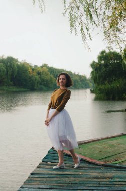 Kharkiv, Ukrayna. 09.19.2021. Şiddetli yağmurda şemsiyeyle nehrin kenarında yürüyen komik bir çiftin aşk hikayesi. Beyaz etekli, sarı kazaklı hoş bir adam ve kadın. Aile tatili ve birliktelik, randevu